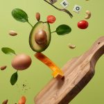 A creative arrangement of paleo diet ingredients floating above a wooden board on a green background.